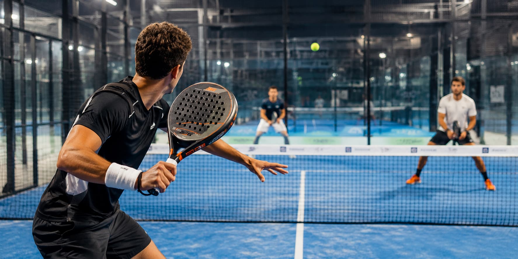 Deux joueurs de padel sur le court, raquette à la main